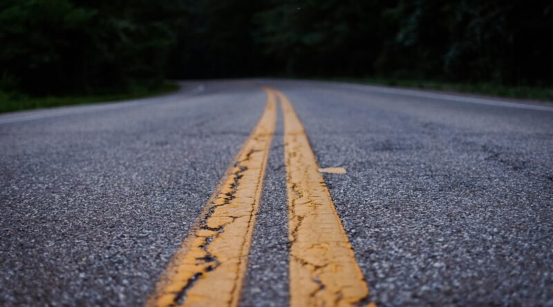 Scenic close-up shot of an empty asphalt road with yellow lines curving through a forested area.