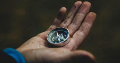 A close-up of a compass held in a dirty hand, symbolizing adventure and navigation.