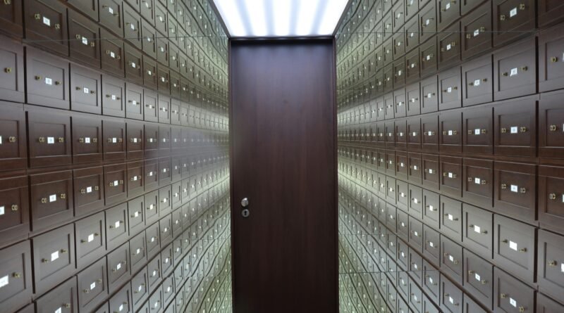 Wooden lockboxes line the walls of a modern, secure vault with a central wooden door.